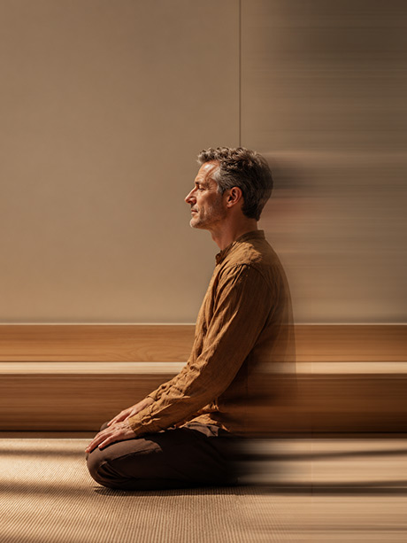 A man seated on a mat in a quiet room
